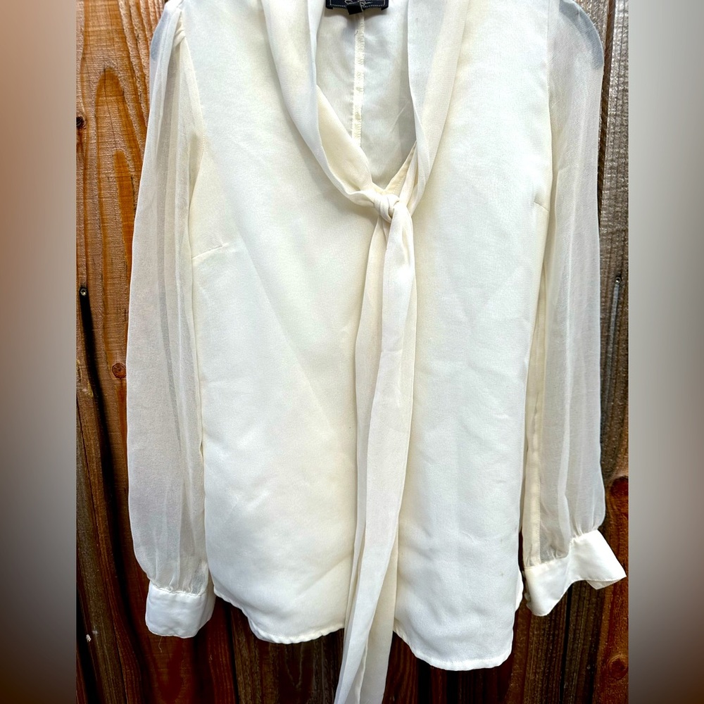 100% Polyester Dress Shirt. 
SIZE: S
COLOR: Cream
BRAND: Jessica Simpson